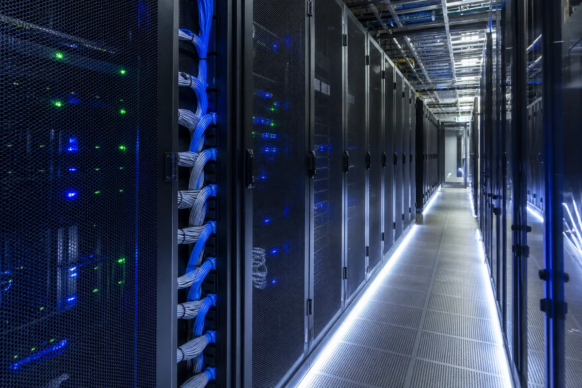 Baie de serveurs aux façades sombres alignées dans une salle technique éclairée en bleu