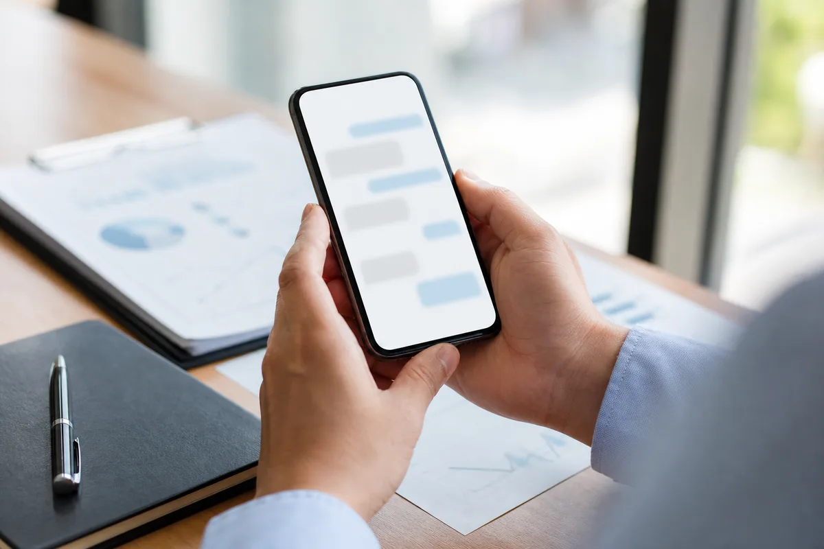 Salarié copiant des notes professionnelles vers un assistant IA sur son smartphone au bureau